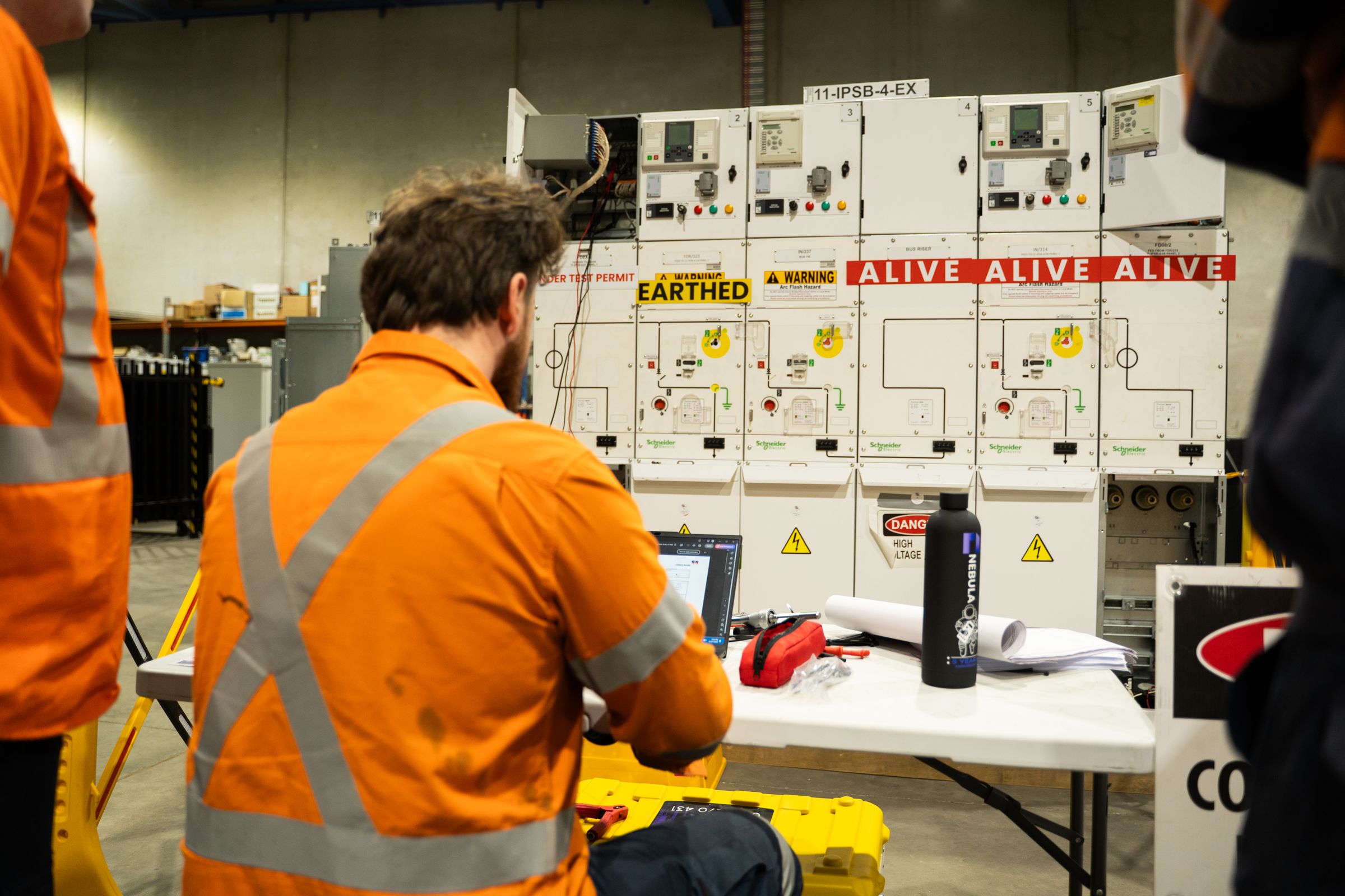 A Nebula technician at a test set and laptop, running injection tests on a switchboard in the training facility