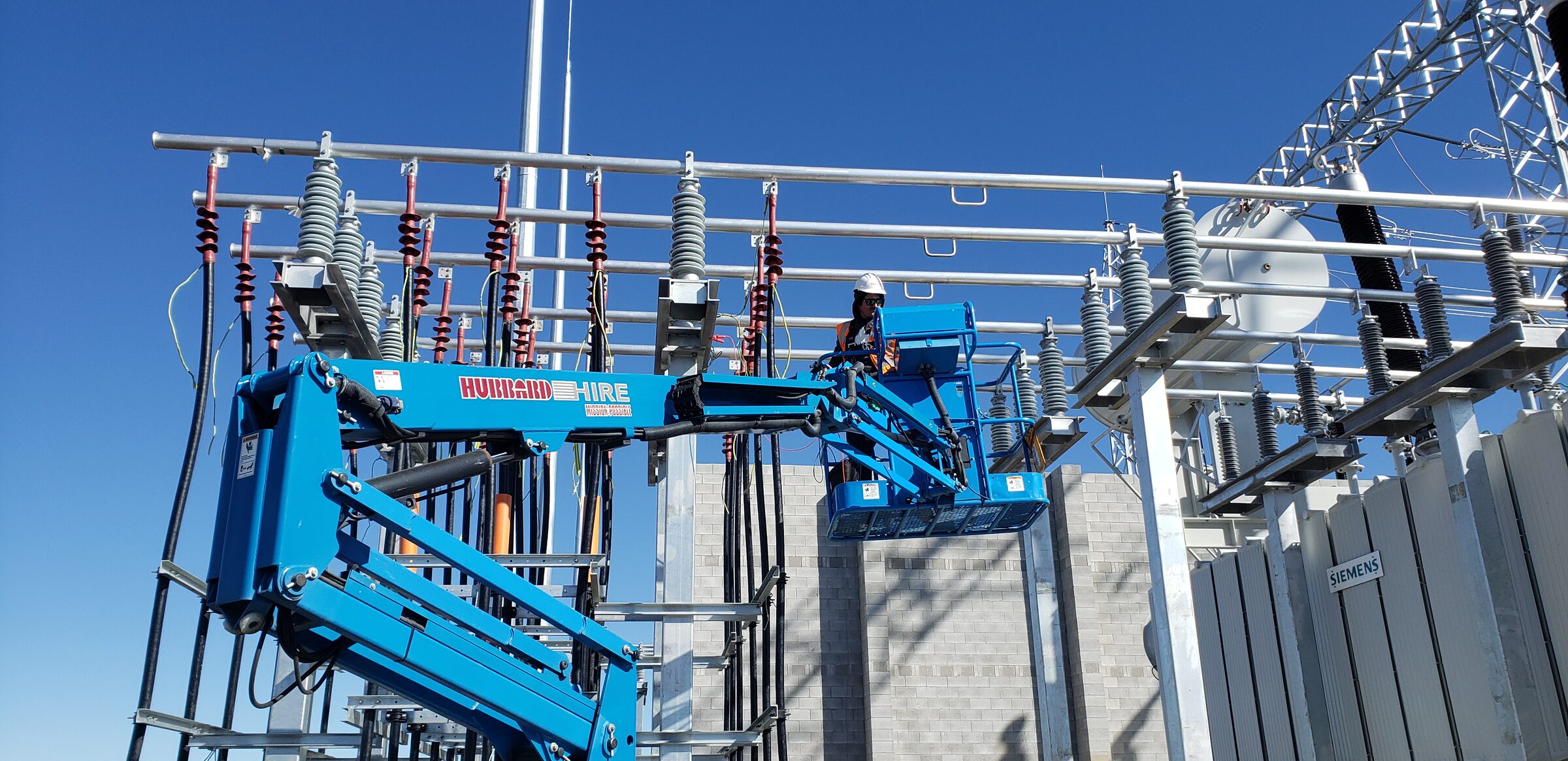 A Nebula electrician in an elevated work platform bolting up switchyard steelwork